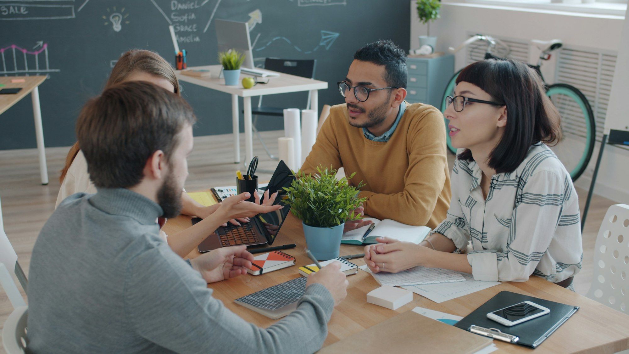 A diverse group of coworkers high-fiving around a table during a meeting
